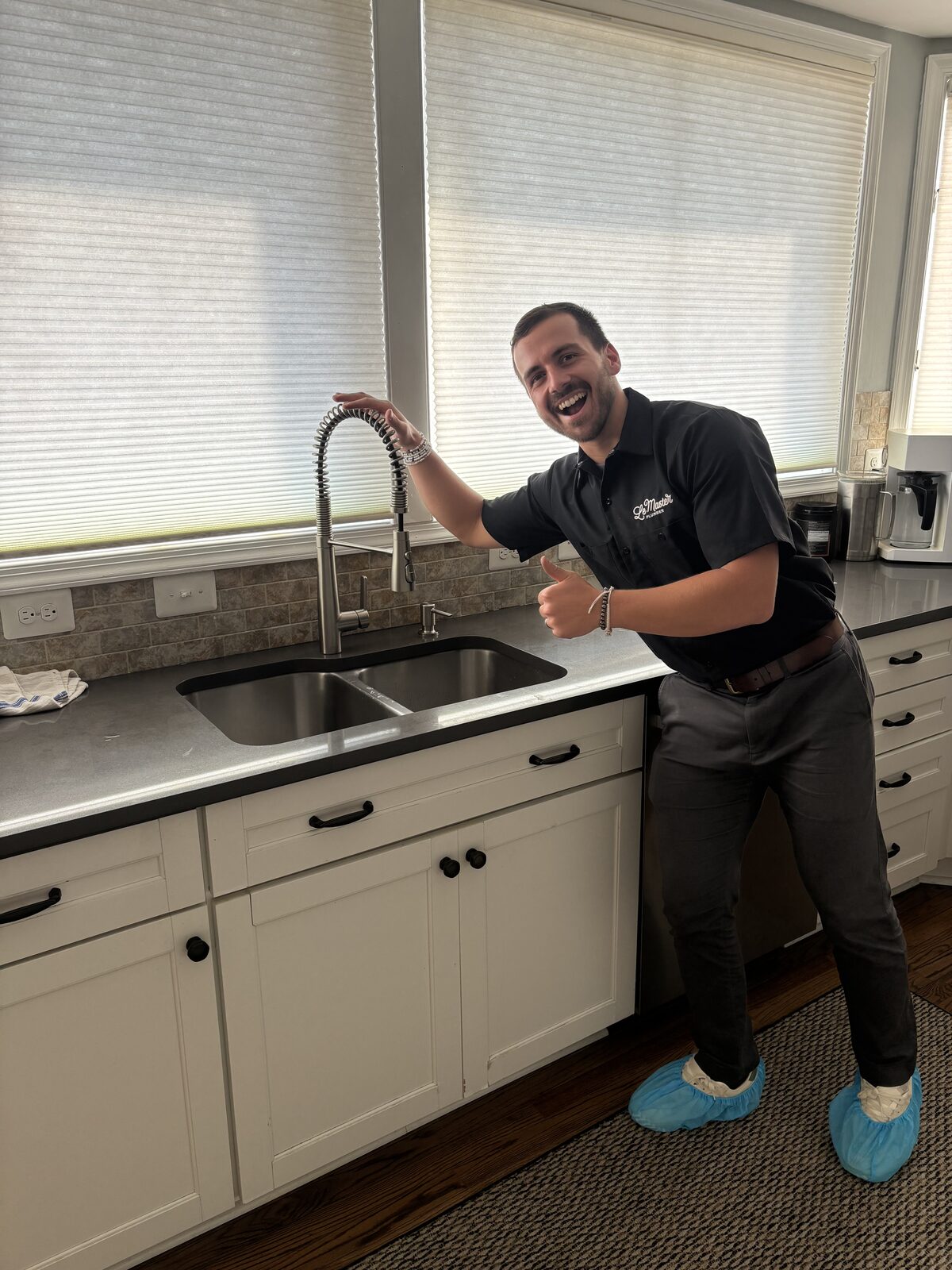 A LeMaster Plumber technician giving a thumbs up beside a newly installed kitchen faucet